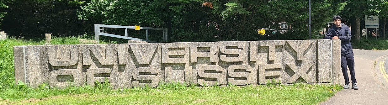 Me with the University of Sussex monument sign, 2024.